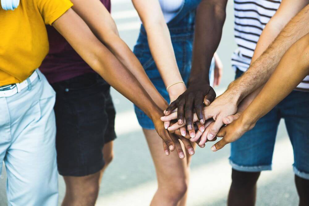 Diverse group of people placing hands in centre